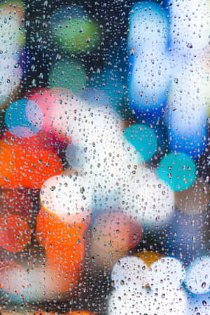 玻璃上的雨滴，背後是模糊多彩的城市燈光。 — 小米平板 9 Pro Max 壁紙