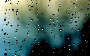 玻璃上的雨滴與模糊的藍綠色和灰色天空背景 — 下雨 壁紙