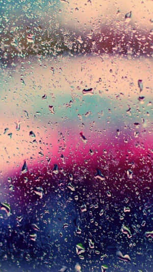 窗戶上的雨滴，背景是色彩繽紛的模糊天空。 — 淺粉色調 壁紙