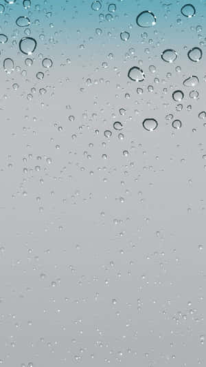 玻璃表面的雨滴，背景為藍色到灰色的漸變。 — iPhone 16 壁紙