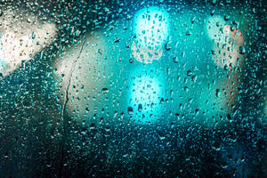 窗戶上的雨滴與夜晚模糊的藍綠色城市燈光。 — 옥자 壁紙