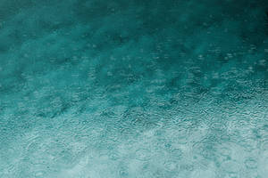 帶有雨滴漣漪和漸變陰影的藍綠色水面 — 秋季 iPhone 壁紙
