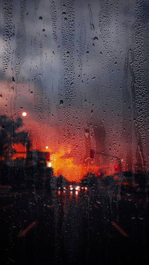 車窗上的雨滴，背後模糊的橙色夕陽交通燈。 — 夕陽天空 壁紙