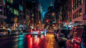 夜晚城市街道，濕漉漉的路面反射來自汽車和建築物的霓虹燈光。 — 紐約 壁紙