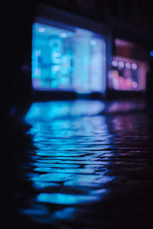 濕漉漉的鵝卵石街道在夜晚反射藍色霓虹燈光。 — POCO Pad X1 壁紙