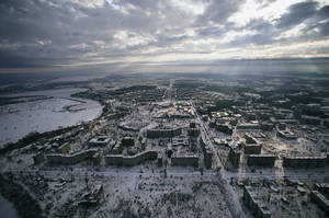 雪覆蓋的城市景觀，多雲天空下，陽光穿透雲層。 — 俄羅斯 壁紙