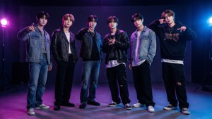 六位時尚年輕男士在紫色和藍色燈光的工作室中擺姿勢。 — Stray Kids 壁紙