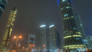 夜晚霧氣瀰漫的城市天際線，閃爍的高樓大廈和街燈。 — 城市 壁紙