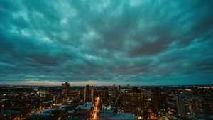 在戲劇性的雲層下，黃昏時分城市天際線閃爍著燈光。 — 青色GIF 壁紙