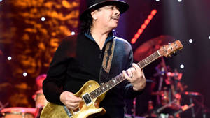 Carlos Santana 在現場音樂會中於舞台上演奏電吉他。 — 音樂 壁紙