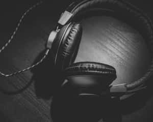 深色木質表面上的頭戴式耳機黑白照 — 5:4 壁紙