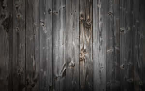 深色風化木板的特寫，帶有可見的木紋和節疤。 — 簡約暗黑美學 壁紙