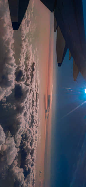 日落時分，飛機翼在橙色和藍色天空中飛越雲層。 — Galaxy S25 FE 壁紙
