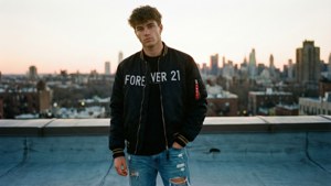 夕陽下，一名男子身著Forever 21飛行員夾克站在屋頂上。 — 永遠21 壁紙