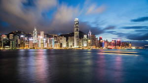 香港天際線在黃昏時分，城市燈光倒映在水面上。 — 香港 壁紙