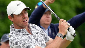 職業高爾夫球手 Rory McIlroy 揮桿中，身穿花卉圖案襯衫和白色帽子。 — 男人 壁紙