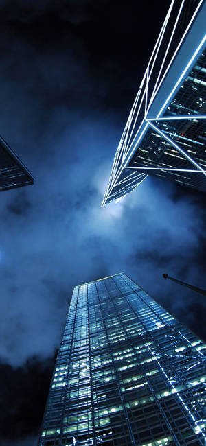 多雲天空下照亮摩天大樓的夜景 — 現代 壁紙