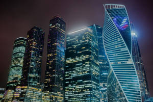密集城市天際線中，現代摩天大樓在夜晚被點亮的景觀。 — 莫斯科 壁紙