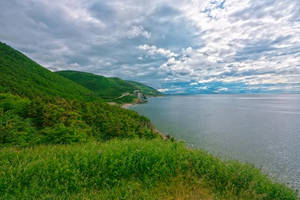 綠色山丘在多雲的天空下與大海相遇。 — 自然風景動圖 壁紙