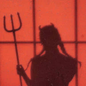 紅牆上帶有網格線的魔鬼手持三叉戟的影子。 — 惡魔角 壁紙