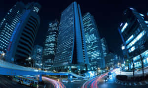 夜晚城市，高樓閃爍，移動車輛留下光軌。 — 城市風景 壁紙