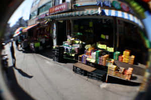 魚眼視角下的熱鬧街市，充滿色彩繽紛的商品和店舖門面。 — 稜鏡 壁紙