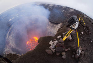 三腳架上的相機俯瞰火山口內發光的熔岩湖。 — 煙動圖 壁紙