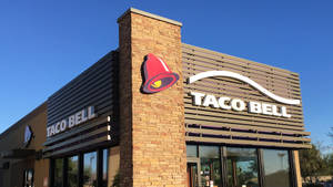 Taco Bell餐廳外觀，紅色鐘形標誌在清澈藍天下 — 塔可 壁紙