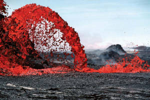 熔岩在火山景觀上方噴發成熾熱的弧線。 — 自然 壁紙