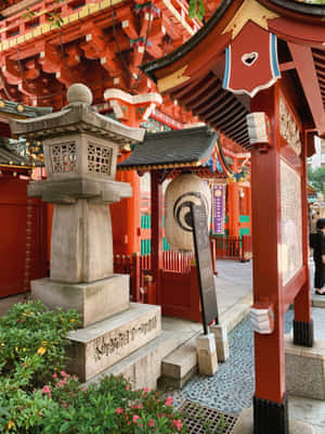 日本神社的紅色鳥居和石燈籠，配以粉紅色的花朵。 — 2048x2732 壁紙