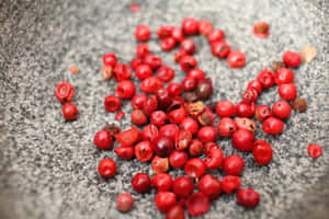 灰色石頭表面上的鮮紅色胡椒粒。 — 粉紅閃光 壁紙