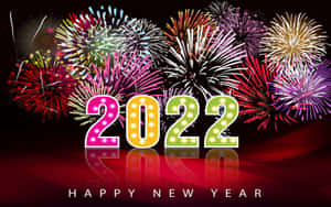 發光的2022年招牌，背後有煙火，映在反射的紅色表面上。 — 新年快樂 壁紙