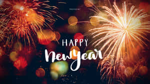 煙火在黑暗的天空中爆發出金橙色，帶有「Happy New Year」文字。 — 慶祝 壁紙