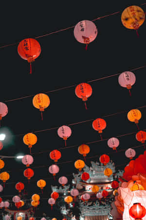 夜晚，寺廟上方懸掛著一排排彩色燈籠。 — 2:3 壁紙