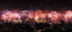 煙火在夜間城市上空爆炸，五彩繽紛的燈光照亮天空。 — 新年 壁紙