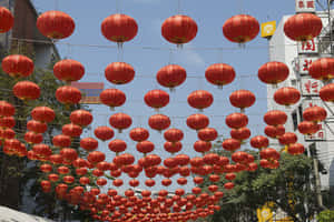 一排排紅色燈籠懸掛在節日氣氛的都市街景上方。 — 春節 壁紙