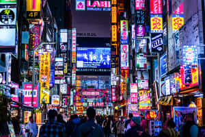 人群在發光的霓虹燈下行走於繁忙的東京夜街。 — 東京 壁紙