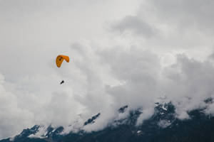 滑翔傘在多雲的天空下飛越雪山。 — 瑞士阿爾卑斯山 壁紙