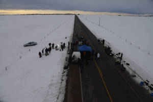 黃昏時分，冰凍田野的雪路上聚集的人群和車輛。 — 雪 壁紙