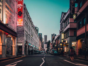 黃昏城市街道，霓虹燈招牌和殖民建築通往現代摩天大樓。 — 街頭 壁紙
