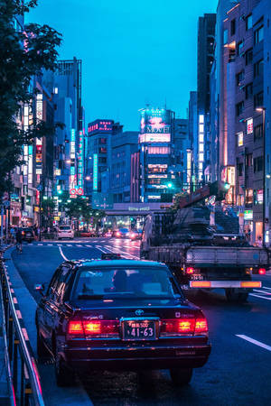 黃昏的東京街道，霓虹燈招牌和汽車在潮濕的路面上 — JDM風格 壁紙