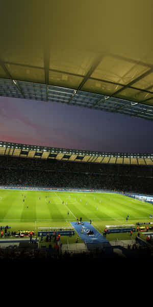 在紫色天空下，黃昏時分在球場燈光下進行中的足球比賽。 — Pixel 3 壁紙