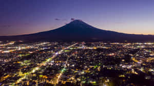 富士山在黃昏時分聳立於發光的城市之上。 — 富士山 壁紙