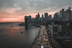 黃昏時分的布魯克林大橋，繁忙的交通和背景的城市天際線。 — MacBook Air 壁紙