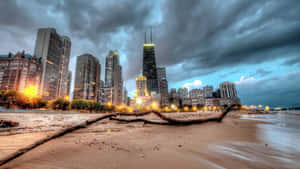 暴風雲下黃昏時分的芝加哥天際線，海灘和前景的倒下的圓木。 — 海灘日落 壁紙