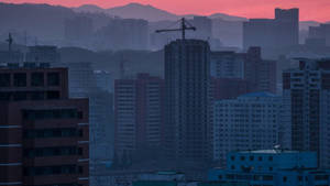 黃昏的城市景觀，高樓和起重機在粉紅色天空的背景下。 — 南韓 壁紙