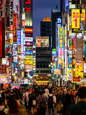夜晚東京擁擠的街道，有發光的霓虹燈招牌和行人。