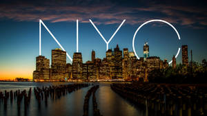黃昏時分的紐約市天際線，發光的NYC字母和寧靜的水面。 — 紐約市 壁紙