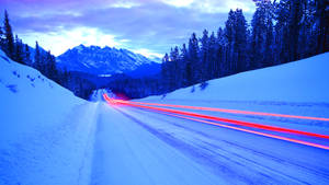黃昏時分積雪的山路，移動車輛留下的紅色光跡。 — 寒冷 壁紙