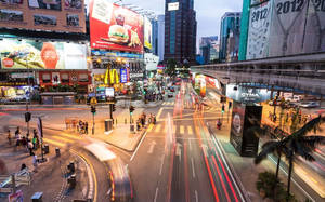 黃昏時繁忙的城市街道，移動車輛的光跡和發光的廣告。 — 台北 壁紙